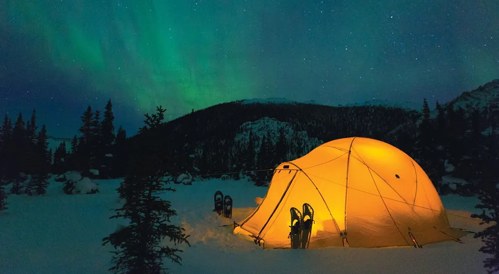 Heated tent glowing under the northern lights